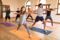 Grupo de pessoas que realizam exercícios de ioga em conjunto no clube de fitness — Fotografia de Stock