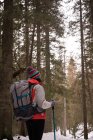 Задумчивая женщина с рюкзаком и походным столбом в лесу — стоковое фото