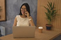 Беременная деловая женщина разговаривает по мобильному телефону за столом в офисе — стоковое фото