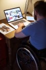 Behinderter junger Mann benutzt Laptop zu Hause — Stockfoto