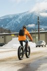 Vue arrière de l'homme faisant du vélo dans la rue pendant l'hiver — Photo de stock