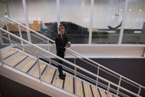 Grafikerin benutzt Handy auf Rolltreppe im Büro — Stockfoto