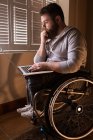 Инвалид молодой человек с ноутбуком дома — стоковое фото