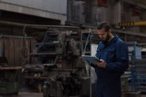 Technicien tenant un dossier sur presse-papiers dans l'industrie métallurgique — Photo de stock
