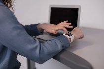 Milieu de section de femme exécutive en utilisant smartwatch sur tapis roulant dans le bureau — Photo de stock