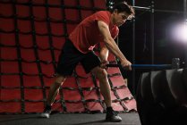 Fitnessmann schlägt mit Vorschlaghammer auf Radreifen in Turnhalle ein — Stockfoto