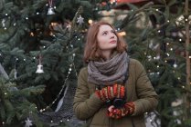 Mujer reflexiva en ropa de invierno sosteniendo la cámara vintage - foto de stock