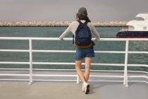 Вид ззаду жінки з рюкзаком, що стоїть на круїзному кораблі — стокове фото