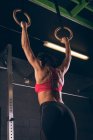 Подтянутая женщина в спортзале подтягивается к гимнастическим кольцам — стоковое фото