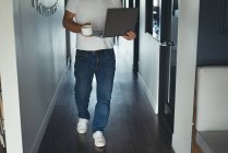 Baixa seção de homem de negócios andando com laptop no escritório — Fotografia de Stock