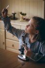 Girl experimenting microscope slide microscope at home — Stock Photo