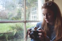 Жінка дивиться фотографії на ретро камеру біля вікна вдома — стокове фото
