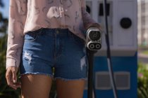Mid section of woman holding a charging plug at charging station — Stock Photo