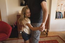 Father and daughter dancing together in living room at home — Stock Photo