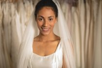 Sinnliche Mischlingsbraut in Brautkleid und Schleier blickt in die Kamera — Stockfoto