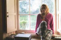 Портрет женщины, отдыхающей у окна дома — стоковое фото