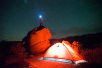 Hombre excursionista de pie sobre roca en el campo por la noche - foto de stock