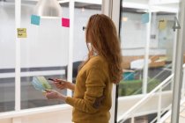 Female executive looking at sticky note in office — Stock Photo