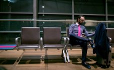Empresário tomando café enquanto espera na área de espera no aeroporto — Stock Photo