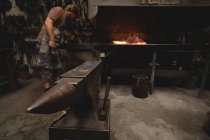 Barra metallica riscaldante di fabbro in fuoco a officina — Foto stock