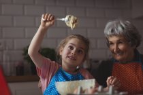 Abuela y nieta preparando galletas en la cocina en casa - foto de stock