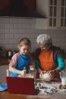 Grandmother and granddaughter preparing cookies in kitchen at home — Stock Photo