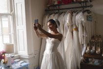 Mariée mixte prenant selfie avec téléphone portable en boutique — Photo de stock