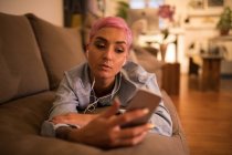 Стильна жінка слухає музику на мобільному телефоні у вітальні вдома — стокове фото