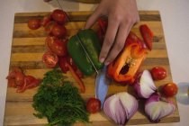 Primo piano della mano della donna che taglia le verdure in cucina a casa — Foto stock