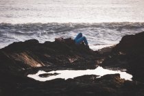 Жінка лежить на скелі на пляжі в сутінках — стокове фото