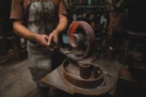 Blacksmith shaping a metal rod in workshop — Stock Photo