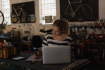 Молода механічна жінка використовує ноутбук у майстерні — стокове фото