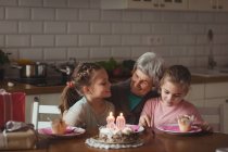 Grand-mère fête son anniversaire avec ses petites-filles à la maison — Photo de stock