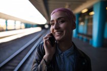 Стильна жінка розмовляє на мобільному телефоні на залізничній станції — стокове фото