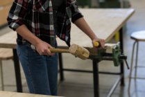 Metà sezione di falegname femminile utilizzando scalpello con martello su un pezzo di legno in officina — Foto stock