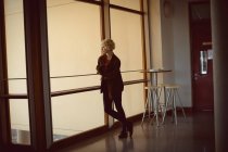 Mulher pensativa de pé perto da janela — Fotografia de Stock