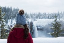 Rückansicht einer Frau mit Blick auf den Wasserfall im Winter — Stockfoto