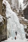 Hombre escalador escalada montaña de hielo durante el invierno - foto de stock