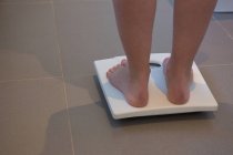 Niedrigschnitt der Frau, die ihr Gewicht zu Hause auf einer Waage überprüft — Stockfoto