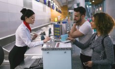 Arline attendant interacting with commuters at counter in airport — Stock Photo