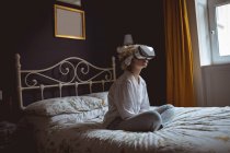 Femme utilisant casque de réalité virtuelle dans la chambre à coucher à la maison — Photo de stock