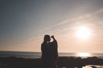 Silhouette di donna in piedi su una spiaggia al crepuscolo — Foto stock