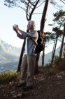 Randonneur senior prenant des photos avec téléphone portable en forêt à la campagne — Photo de stock