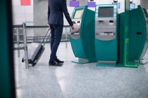 Empresario que utiliza la máquina de billetes de avión en el aeropuerto - foto de stock