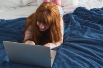 Mulher com cabelo vermelho usando laptop no quarto em casa — Fotografia de Stock
