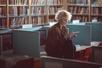 Giovane donna utilizzando tavoletta digitale in biblioteca — Foto stock