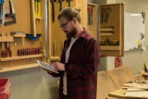 Плотник-мужчина с помощью цифрового планшета в мастерской — стоковое фото
