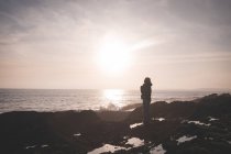 Silhouette di donna in piedi su una spiaggia al crepuscolo — Foto stock