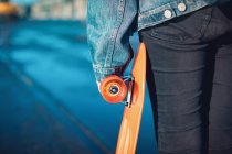 Mid section of woman holding a skateboard — Stock Photo