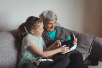 Nonna e nipote in possesso di cuffia realtà virtuale in soggiorno a casa — Foto stock